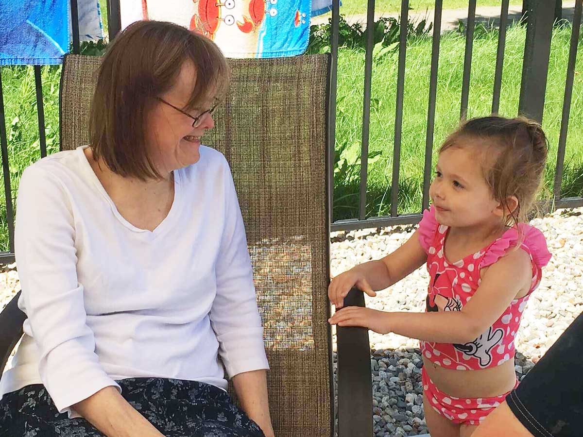 Jane and a preschooler smiling at each other outdoors