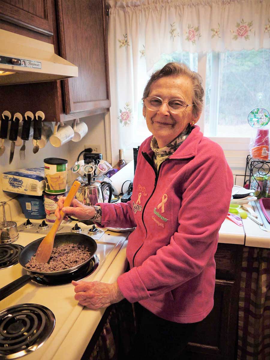 Mary cooks ground beef on Jean's stove