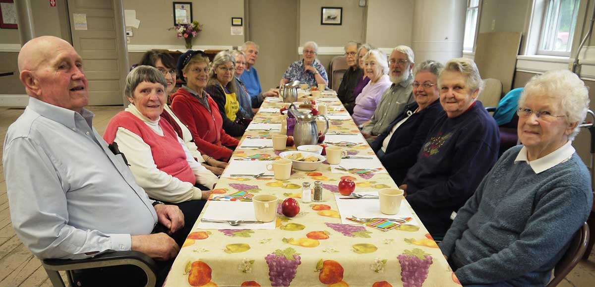 Group photo of older adults at a communal table