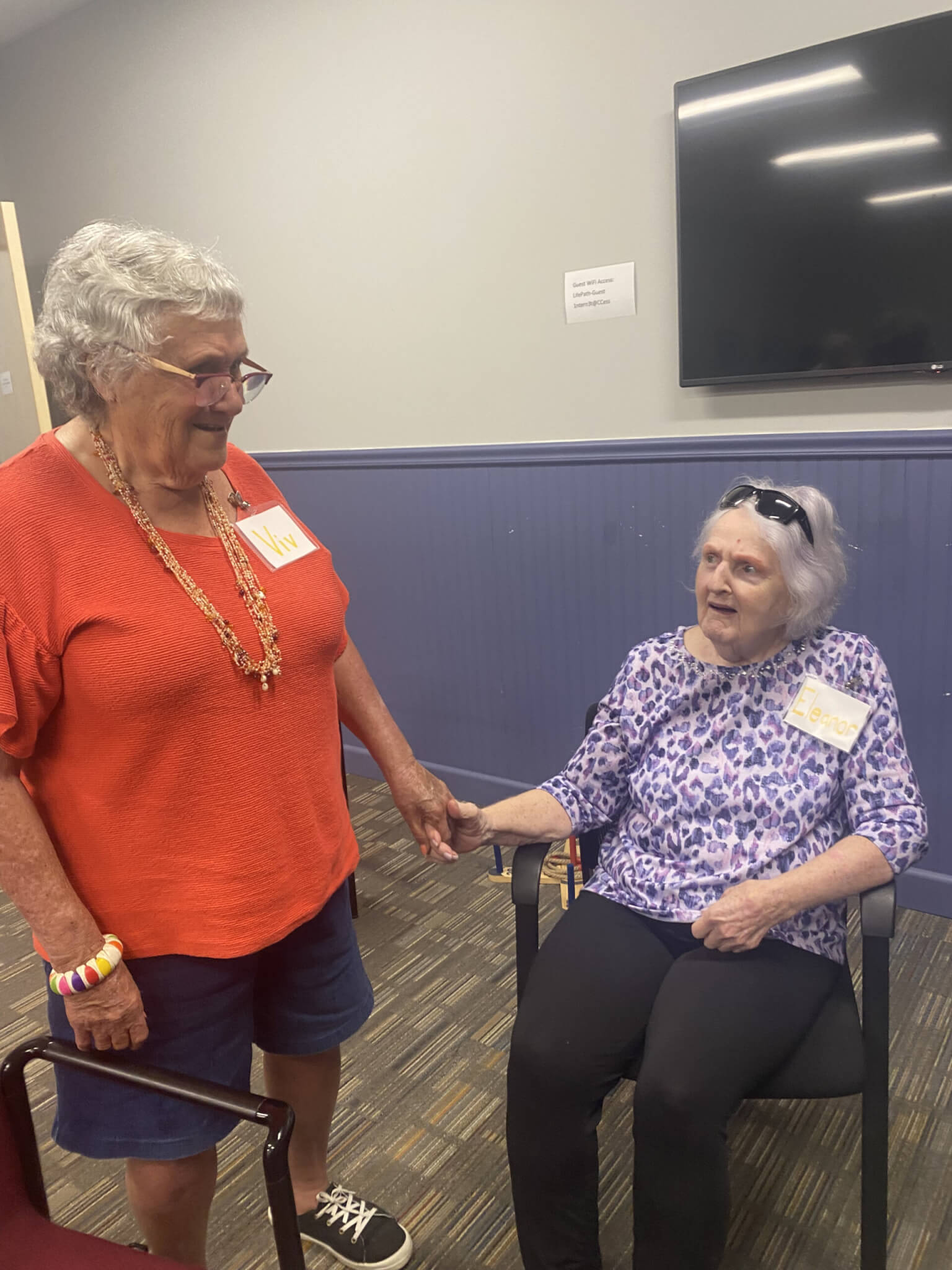 standing older woman greeting sitting older woman at CEC