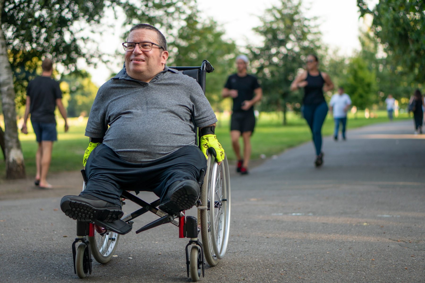 Man smiling in wheelchair ambulating in a part.