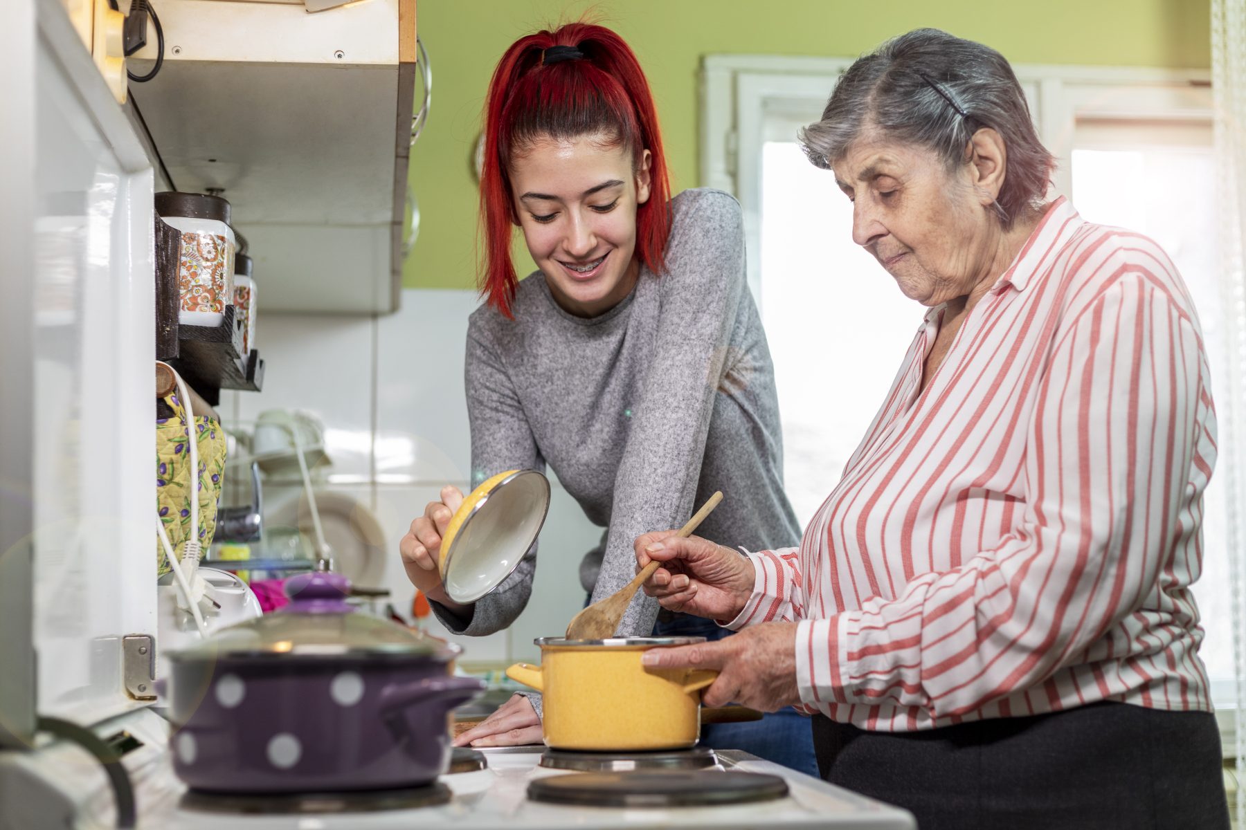 Young woman helping older woman cook at the stove.