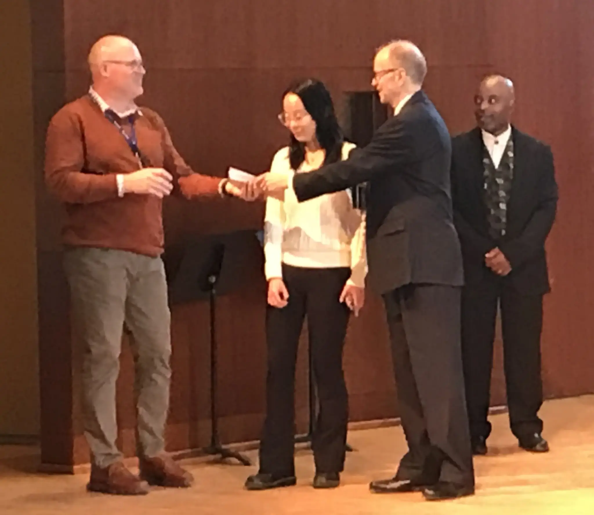 Gary Yuhas, Executive Director at LifePath, receiving a check from Steven Bathory-Peeler, with Grace Huang, student representative for the Penguin Pals Student Club, and Ron Smith, Director of Music Programs for NMH, looking on. NMH raised over $1,000 for LifePath’s programs.