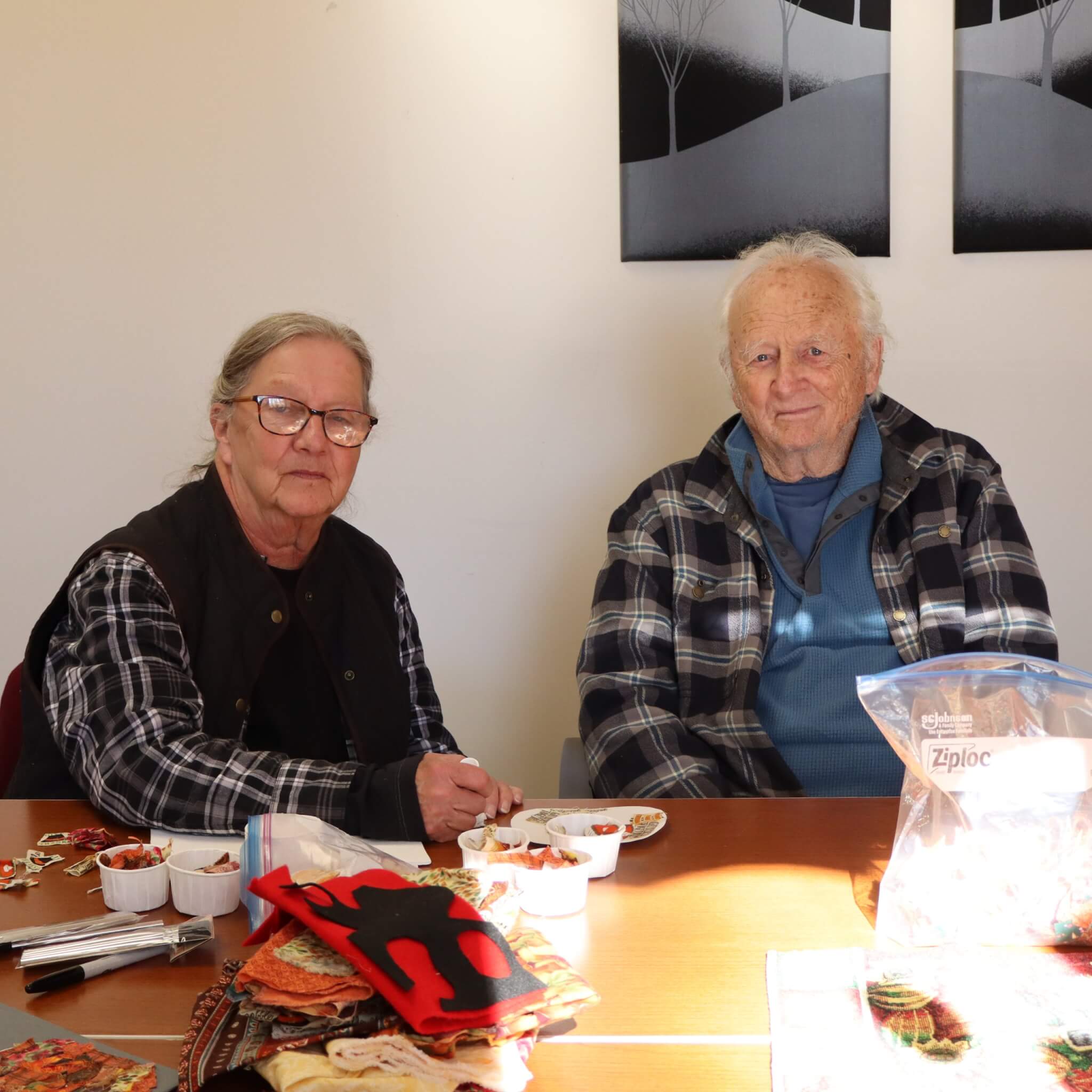 older woman sitting at table with older man doing activities