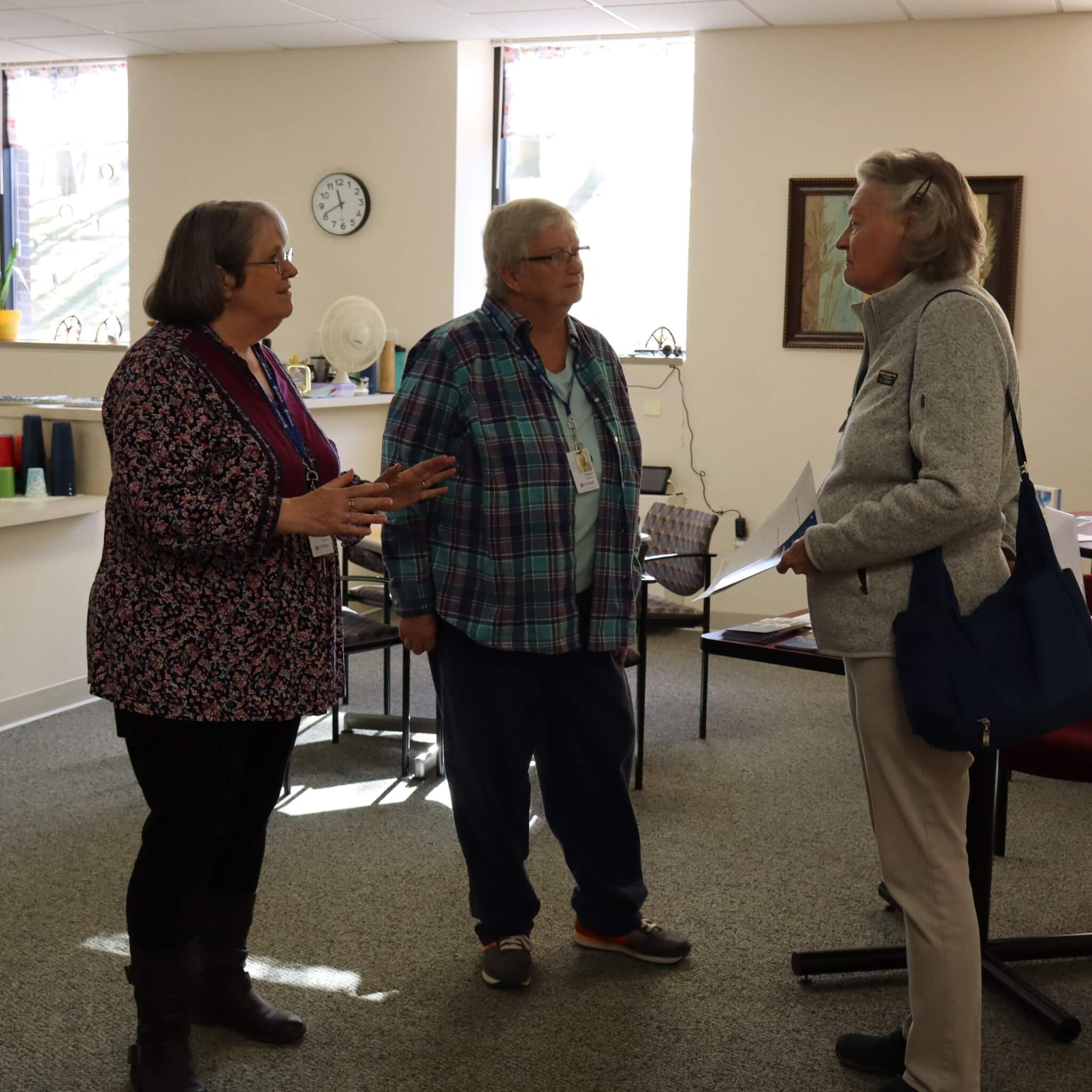 three women standing and conversing in a building