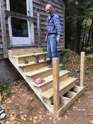 A volunteer works on rebuilding an outdoor wooden stairway