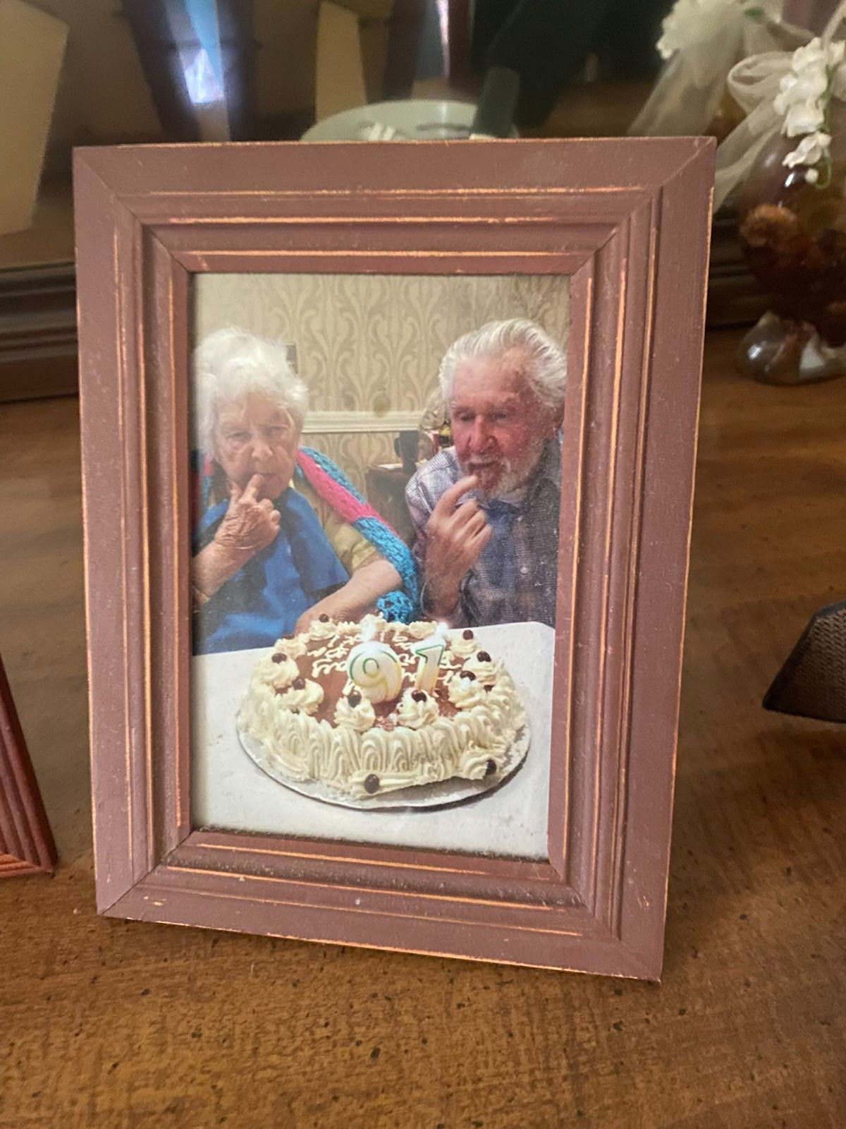 Framed photo of George and Marvette Selanis with a 91st birthday cake