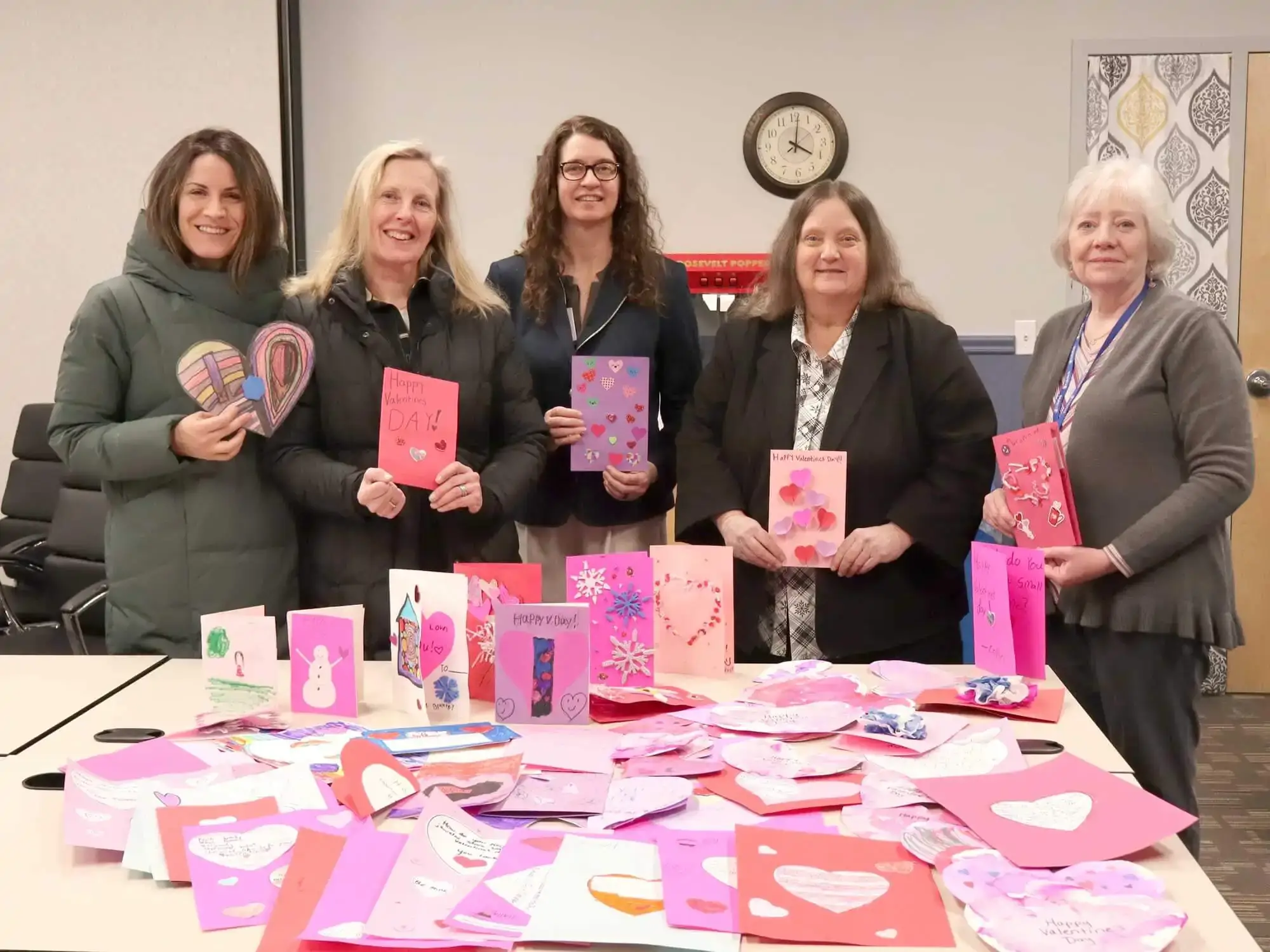 Five people posing with a table full of homemade valentines