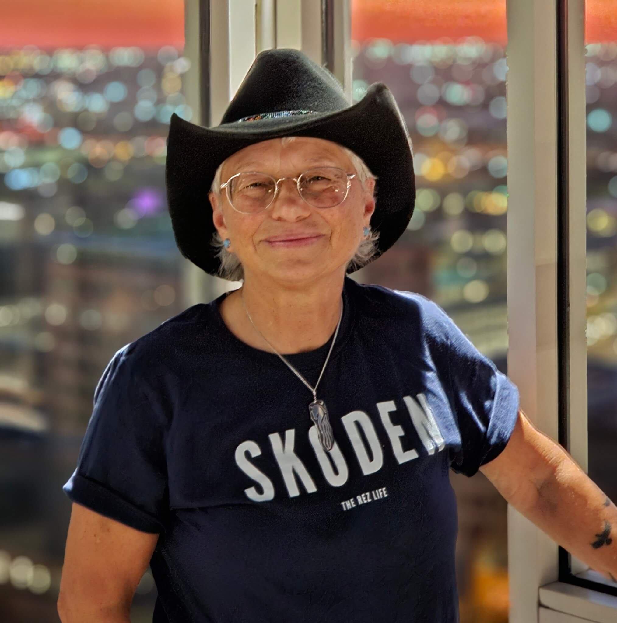 Cris Carl, with western hat, standing in front of window in tall building