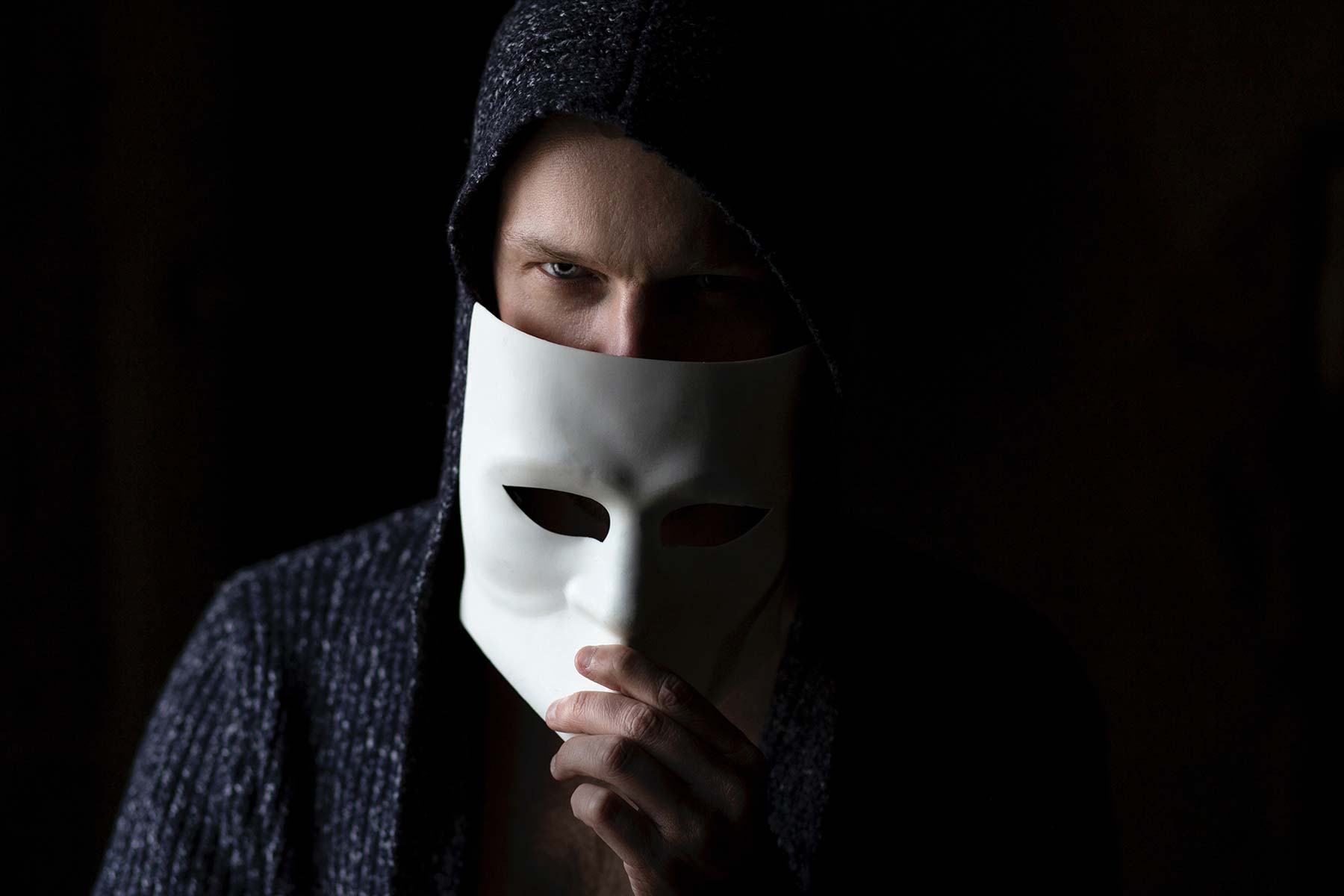 A scammer wearing a hood and mask