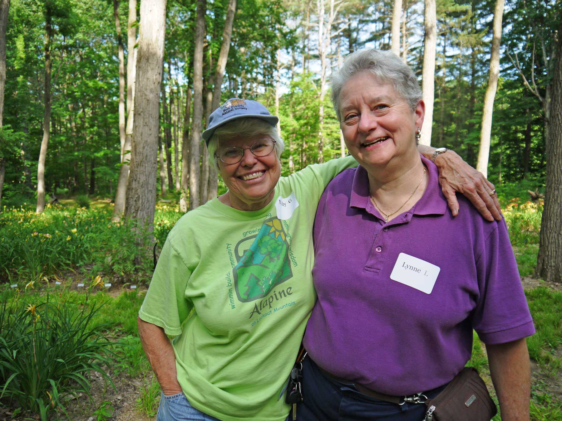 Two members of Rainbow Elders, smiling with their arms around each other outdoors