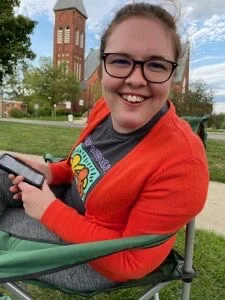 smiling woman with glasses sitting outside in the sun