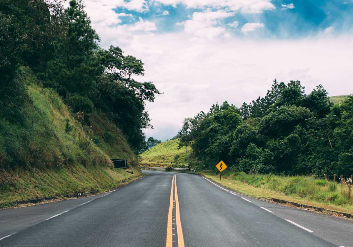 empty road with grassy hills on each side from perspective of driver