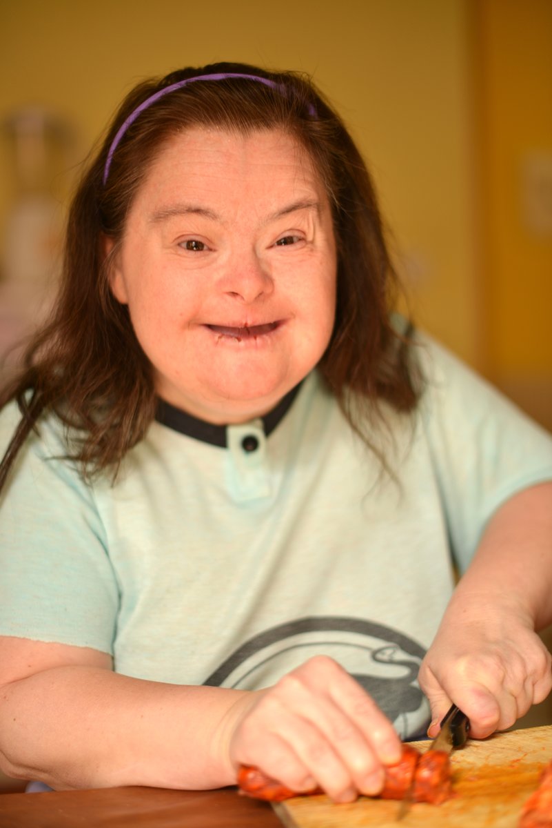 picture of happy woman with Downs Syndrome cutting a carrot