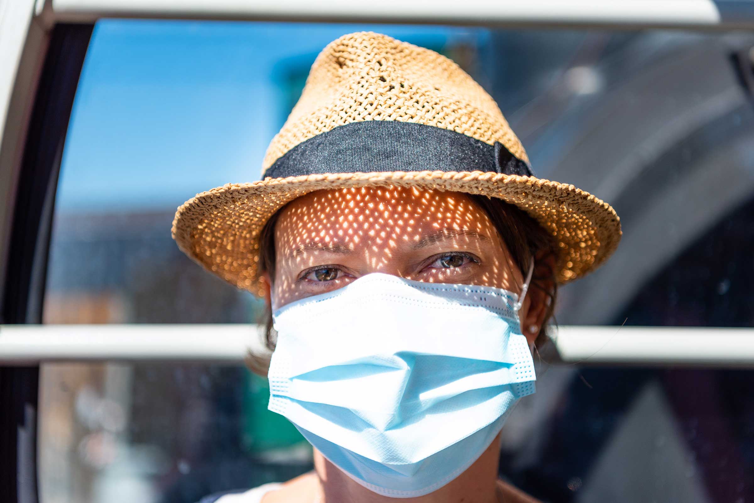 Happy woman wearing surgical mask in sunlight