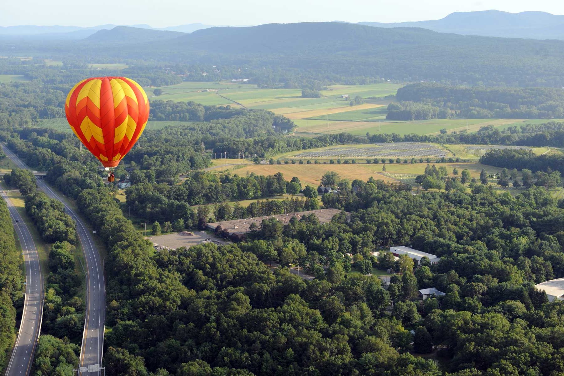 Aerial view of a hot air balloon floating over fields and woods in Franklin County, Massachusetts