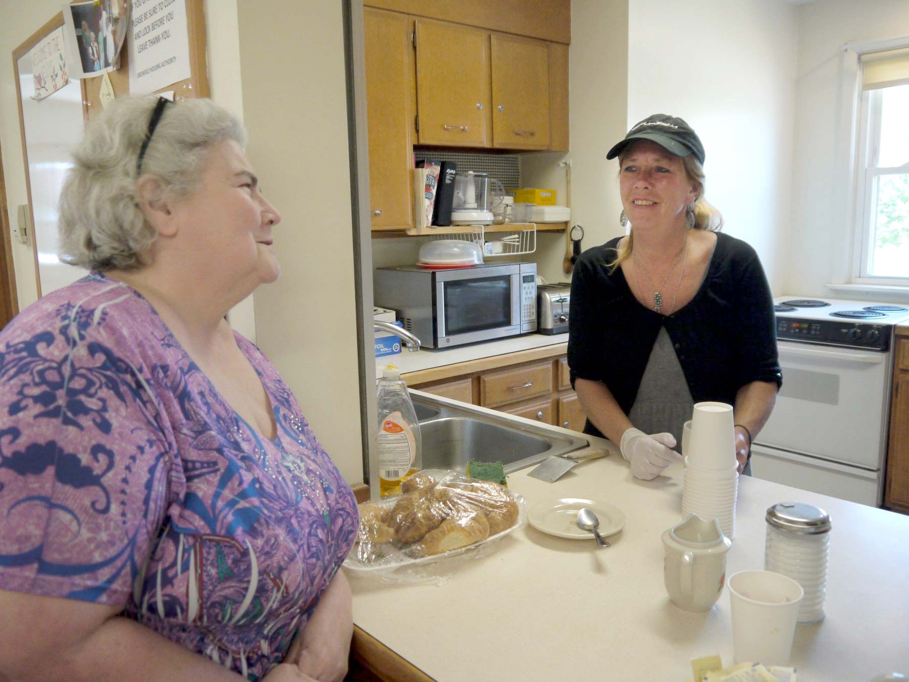 Two women in a communal kitchen smiling.